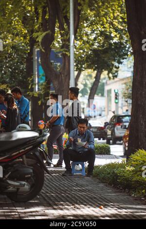 Saigon, Vietnam - 4 luglio 2020: Le strade di Saigon (ho Chi min City), scena di persone che hanno la colazione sul marciapiede di un carrello che porta cibo. Foto Stock