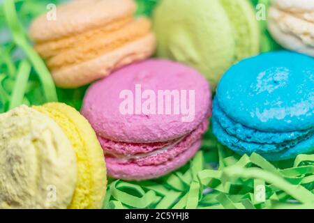 amaretti da dessert francesi teneri di diversi colori su carta a strisce verdi Foto Stock