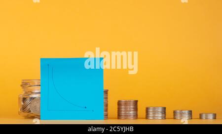 crisi finanziaria. pila di monete con un grafico per una caduta. Foto Stock