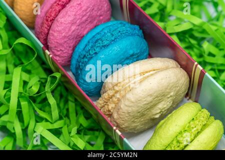 amaretti da dessert francesi teneri di diversi colori su carta a strisce verdi Foto Stock