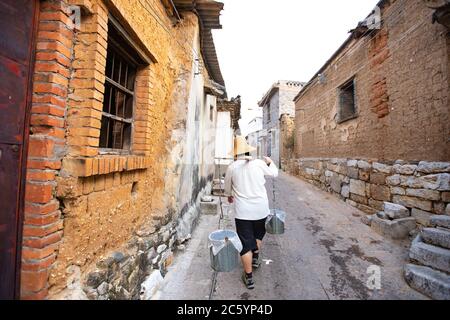 Un uomo che porta acqua in un vecchio modo a Yunnan, in Cina. Foto Stock