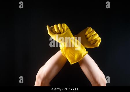 mani in guanti di gomma gialli su fondo nero. Foto Stock