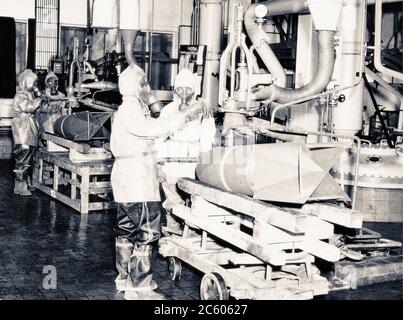 Foto di lavoratori tedeschi in speciali indumenti protettivi distruggono bombe tossiche il 28 giugno 1946, presso il deposito US Army Chemical Warfare Service, a St. Foto Stock