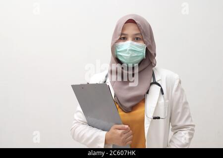 Donna musulmana che indossa hijab e tuta, in piedi con maschera protettiva viso, pronto a combattere coronavirus covid19 pandemia globale Foto Stock