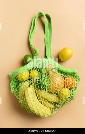 Shopping borsa verde con frittelle, limone, lime, banana su beige. Zero sprechi. Vista dall'alto. Foto Stock