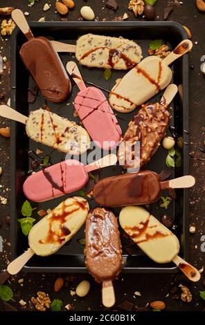 Assortimento di vari gelati a base di papsicle, cioccolato bianco e scuro, con mandorle, fondo arrugginito Foto Stock