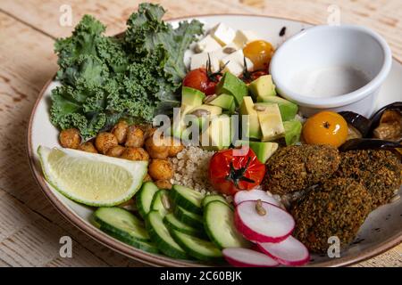 Piatto sano di pollo all'avocado quinoa, pomodori ciliegini e verdure su sfondo di legno. Foto Stock