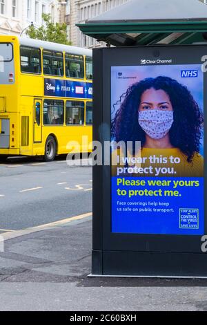 I rivestimenti del viso ci aiutano a mantenere al sicuro sui trasporti pubblici controllo di allarme il virus salvare vite poster con Yellow bus dietro a Bournemouth, Dorset UK Foto Stock