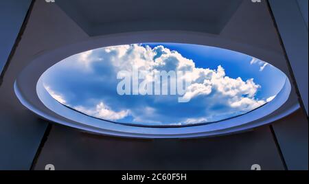 Architettura circolare in cemento, vista dal basso fino alle nuvole bianche e al cielo blu, interni moderni e contemporanei. Concentratevi sui cloud. Foto Stock