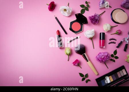 cosmetici per il trucco e attrezzature con fiori su sfondo rosa con spazio per la copia. vista dall'alto Foto Stock