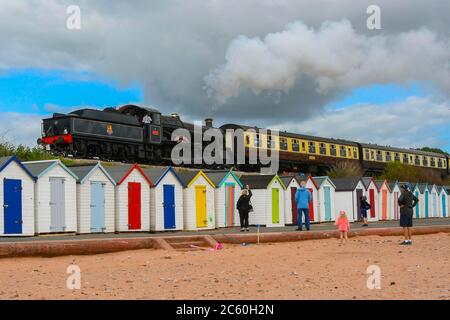 Goodrington Sands, Paignton, Devon, Regno Unito. 6 luglio 2020. La ferrovia a vapore di Dartmouth riapre con il primo treno passeggeri del giorno, durante la sua riapertura trainato da 7827 Lydham Manor passando dietro le capanne sulla spiaggia a Goodrington Sands sulla sua strada per Kingswear dopo aver lasciato la stazione a Paignton in Devon dopo l'ulteriore allentamento delle regole di blocco del coronavirus permesso alla linea heritage di trasportare nuovamente i passeggeri. Immagine: Graham Hunt/Alamy Live News Foto Stock