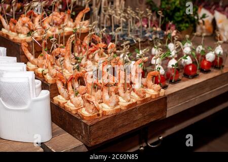 Buffet di nozze. Gamberi con crostini su un supporto in legno Foto Stock