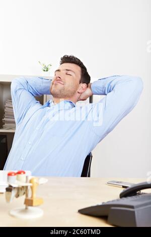 Il manager rilassato in ufficio si appoggia alla scrivania Foto Stock
