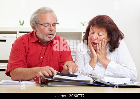 Gli anziani scioccati nel meno guardare una calcolatrice alla scrivania Foto Stock