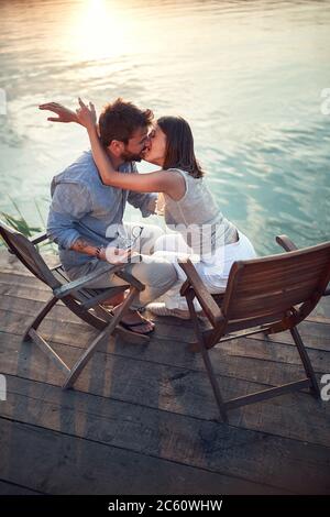 giovane coppia seduta sul fiume, abbracciando e baciando Foto Stock
