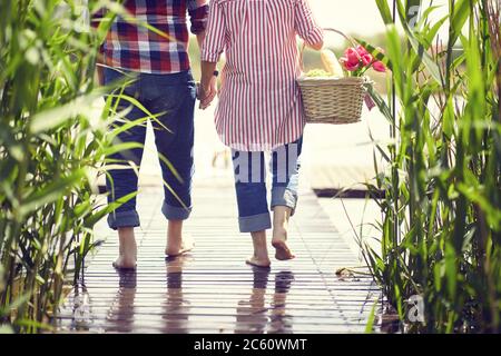 Senior vicino stagno. Nonni durante va sullo stagno al picnic. Vista posteriore Foto Stock