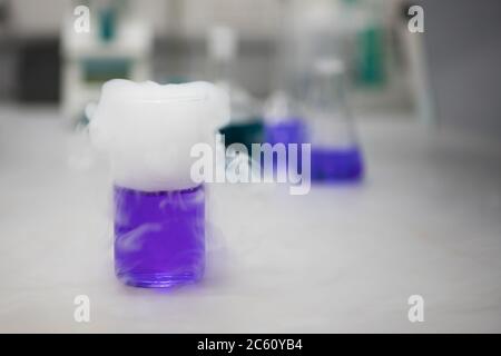 Fumare soluzioni chimiche viola in un laboratorio scientifico. Chimica analitica Foto Stock
