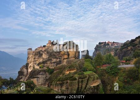 Monasteri di Meteora. Bella vista sul Monastero Santo di Varlaam posto sul bordo di alta roccia coperta delle nuvole del mattino e nebbia all'alba Foto Stock