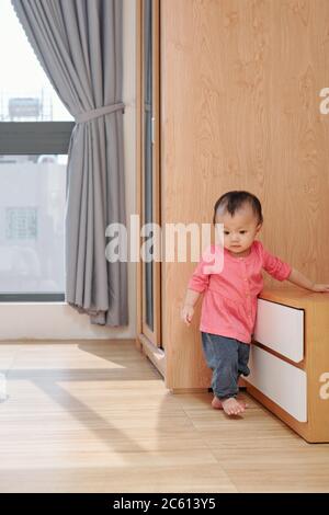 Piccola ragazza vietnamita che cammina in soggiorno quando si esplora l'appartamento Foto Stock