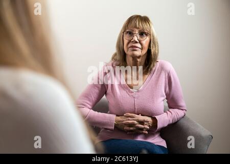 Donna anziana in consultazione con il suo psicologo. Donna preoccupata che è curata dal suo terapeuta. Foto Stock