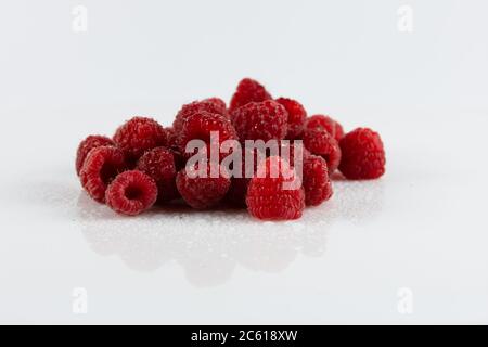 diversi lamponi rossi con gocce d'acqua su sfondo chiaro Foto Stock