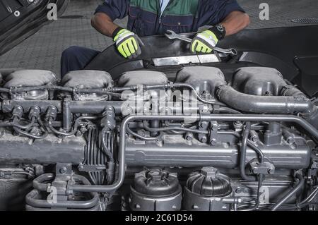 Il tecnico dei motori diesel per veicoli pesanti effettua la manutenzione programmata rimanendo davanti al moderno motore semi-camion. Foto Stock