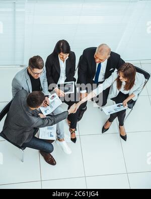 vista dall'alto. colleghi di lavoro che scuotono le mani durante una riunione d'ufficio . Foto Stock