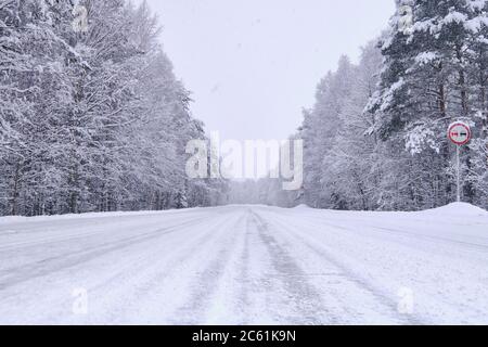 Strada di campagna coperta di neve bianca chiara. Foresta coperta di neve Foto Stock