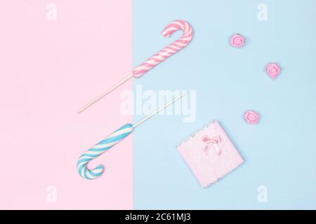 Due canne caramelle con scatola regalo su sfondo blu pastello e rosa. Vista dall'alto, disposizione piatta. Congratulazioni concetto minimo femminile Foto Stock