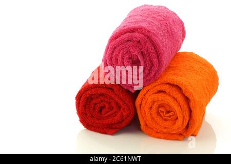 colorati asciugamani da bagno arrotolati e accatastati su uno sfondo bianco Foto Stock