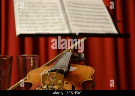 Violino con prua e spartiti con messa a fuoco selettiva e sfondo in cortina rossa, fuoco selettivo, alla scuola di musica in Brasile, Sud America Foto Stock