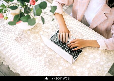 Donna seduta al tavolo e che lavora al computer portatile. Foto Stock