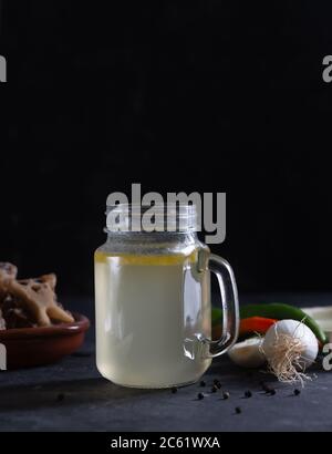 Brodo di manzo fatto in casa in vetro vaso di stoccaggio su sfondo nero Foto Stock