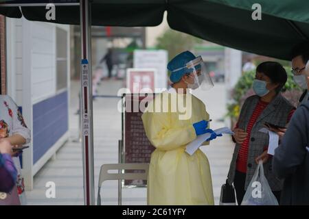 Medico che parla con i visitatori all'ingresso dell'ospedale, indossando maschera facciale e indumenti protettivi per evitare il coronavirus. Foto Stock