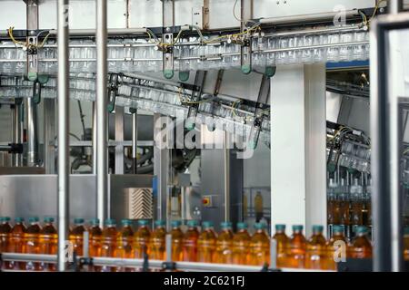 Bottiglie in plastica con succo sulla linea di trasporto o sul nastro in una moderna fabbrica di bevande. Foto Stock