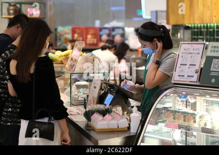 cassiere in caffetteria, indossando la maschera facciale per evitare il coronavirus covid-19 Foto Stock