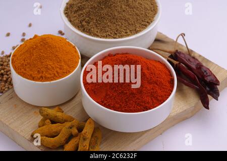 Closeup di spezie indiane Chili, curcuma e coriandolo sono le tre spezie di base utilizzati per curry indiano o piatti, disposti in ciotole bianche Foto Stock