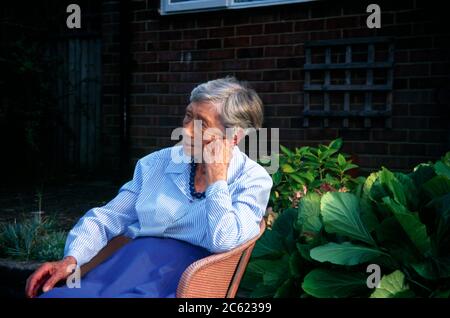 Donna di novanta anni seduta su sedia fuori Inghilterra Foto Stock