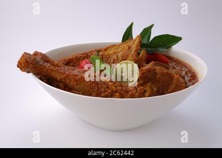 Curry di montone o curry di agnello, piatto piccante e delizioso guarnito con foglie di curry che è usato in piatti del sud-est asiatico, fette di limone e peperoncino rosso Foto Stock