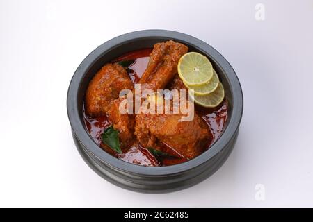 Curry di montone o curry di agnello, piatto piccante e delizioso guarnito con foglie di curry e fette di limone in un vaso nero con tessitura bianca o sfondo, AN Foto Stock