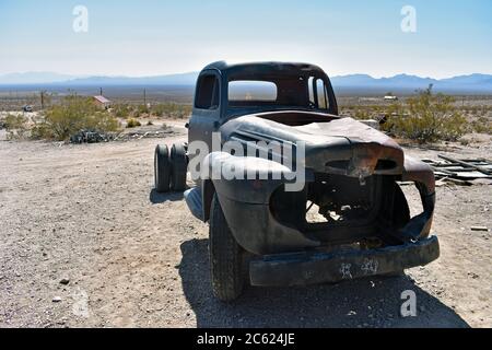 Un veicolo abbandonato pick up / camion nel deserto del Nevada con le montagne. Città fantasma di Rhyolite una città mineraria abbandonata vicino al Parco Nazionale della Valle della morte Foto Stock