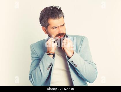 Ritratto di uomo d'affari senior con barba, molto congelato in tuta blu e in piedi su sfondo bianco. Foto Stock