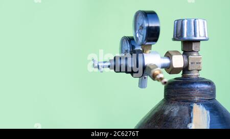 bombola di gas in metallo grande con strumenti di misurazione e scatole ingranaggi su sfondo verde. Foto Stock