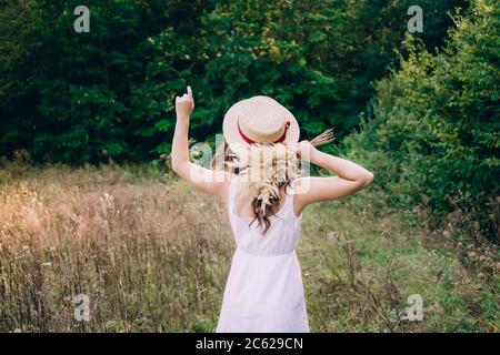 Giovane donna con capelli ricci in un cappello. Ragazza snella in un cappello con la schiena girata. Foto di una ragazza dalla parte posteriore. Foto Stock