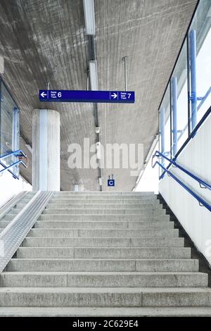 L'interno della stazione ferroviaria locale, cemento non dipinto e cartelli blu. Foto Stock