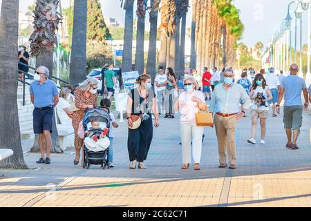 Huelva, Spagna - 3 giugno 2020: Persone che camminano dalla passeggiata Islantilla al tramonto indossando maschera protettiva a causa di covid-19. Foto Stock