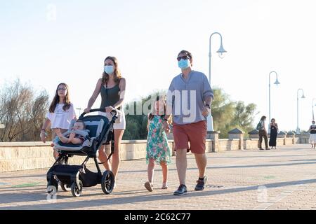 Huelva, Spagna - 3 giugno 2020: Passeggiata in famiglia con la passeggiata di Islantilla indossare maschera protettiva a causa di covid-19. Foto Stock