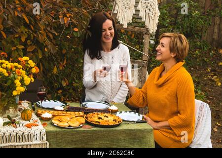 Pranzo in famiglia nel cortile. Donne-uomini bere vino e ridere. Foto Stock