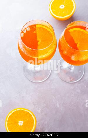 Cocktail Aperol spritz su sfondo grigio. Due bicchieri di aperol Spritz con scorza d'arancia. Cocktail estivo in vetro. Vista dall'alto. Spazio di copia Foto Stock