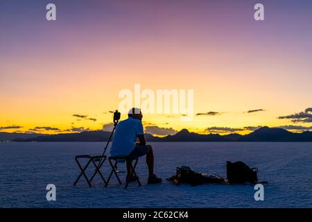 Bonneville Salt Flats vicino a Salt Lake City, Utah al crepuscolo scuro colorato dopo il tramonto con colore viola e fotografo uomo seduto a guardare vista wi Foto Stock